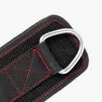 Close-up of a black fabric fitness strap with red stitching and a silver metal D-ring on a plain white background.