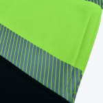 Close-up of neon green safety fabric with a reflective grey striped band and black material.