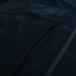 Close-up view of a dark blue softshell jacket featuring a zippered pocket and clean stitching.