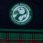 A circular green logo featuring a puffin head and the text 'Irving Aviation Newfoundland Puffins' on a dark blue background with a green and red plaid pattern at the bottom.