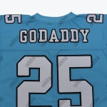 Close-up of the back of a light blue jersey showing the name GODADDY and the number 25 in white block letters with black outlines.