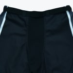 Close-up of the waistband of black athletic pants with an integrated belt and white side stripes.