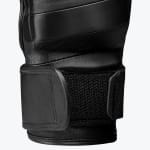 Close-up view of a black leather boxing gloves wrist strap, showing the textured hook-and-loop fastener and stitching details.