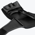 Close-up of the open palm side of a black leather MMA grappling glove with finger loops and a wrist strap.
