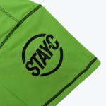 Close-up of a neon green sleeve with a black circular logo that reads STAY-C and black stitching.