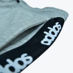 Close-up of grey heathered sweatpants showing a pocket and a black trim band with the white Addos logo.