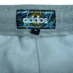 Close-up of a rectangular Addos Workwear Collection label on a grey ribbed waistband, showing white embroidered branding and a small black size L tag.