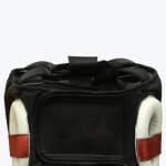 Close-up of the back of a black boxing headgear showing the hook-and-loop closure strap and white ear protectors with a red stripe.