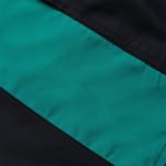 Close-up of a smooth synthetic fabric with a diagonal color-blocked pattern of black and teal green, separated by neat stitched seams.