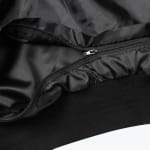 Close-up view of a black jacket zipper, shiny inner lining, and ribbed knit hem.