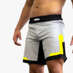 A man wearing grey athletic shorts with black and neon yellow accents and a black waistband featuring the Addos logo.
