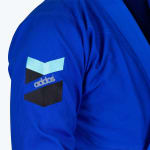 Close-up of a blue Addos martial arts gi sleeve showing the embroidered chevron logo.