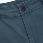 Close-up of a pair of teal twill trousers showing the waistband, stitching details, and a dark brown button.