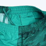 Close-up of the inside waistband of teal athletic shorts, showing a small internal pocket, an elastic waist, and a crossed drawstring.