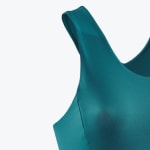 Close-up view of a teal green sports bra strap and neckline showing the smooth, seamless fabric texture.