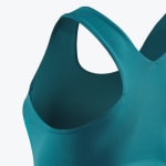 Close-up view of a teal athletic sports bra showing the shoulder strap and armhole fabric detail.