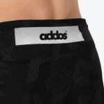 Close-up of the back waistband of black patterned athletic shorts, featuring a white rectangular patch with the black Addos logo.