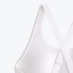 Close-up of a white sports bra showing the crossed back straps with adjustable sliders.