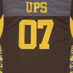 The back of a brown and grey sports jersey with UPS printed in yellow at the top and the number 07 in large yellow font below it.