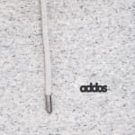 Close-up of grey speckled hoodie fabric featuring a hanging grey drawstring with a silver metal tip and the black printed text addos on the right.
