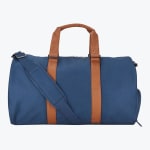 A navy blue duffel bag with brown leather handles and straps, featuring a matching blue adjustable shoulder strap, set against a plain white background.