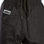 Close-up view of the elastic waistband and drawstring of black pants, featuring a white rectangular label with the text addos on the left side.