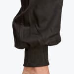 Close-up of a black ribbed elastic cuff on a pair of jogger pants against a white background.