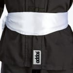 Close-up of a black martial arts uniform with a wide white satin sash tied around the waist.