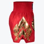 Side view of red satin Muay Thai shorts featuring a metallic gold flame pattern on the side slit against a plain white background.