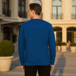 Rear view of a man wearing a plain royal blue sweatshirt and black pants, standing outdoors in front of a building.