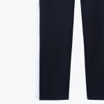 Close-up of the lower portion of navy blue track pants featuring a thick white stripe on the outer leg.