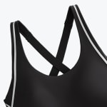 Close-up of a black sports bra with white piping detail on the straps and a criss-cross back design.