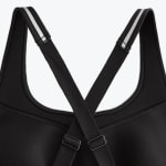 Close-up of the back of a black sports bra showing the adjustable criss-cross straps with a white stripe detail on the shoulders.