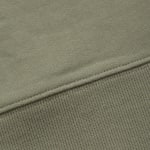 Close-up of a sage green fabric showing the seam between a smooth knit sweatshirt material and a ribbed knit cuff.