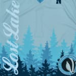 A light blue jersey with Lost Lake written vertically, a pine tree forest graphic, and a Wisconsin badger pilsner logo.