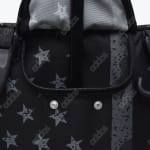 Close-up of a black Addos bag with a star pattern, showing a zipper, metal snaps, and a trolley handle.