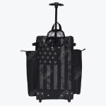 A black rolling bag with a distressed grey American flag print, featuring an extended handle, wheels, and side pockets against a white background.