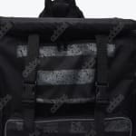 Close-up of a black Addos backpack featuring a grey speckled striped pocket and two vertical buckle straps.