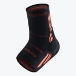 A black and orange knitted compression ankle sleeve designed for athletic support.