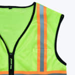 Close-up of a neon green mesh safety vest with orange and silver reflective stripes and a black zipper.