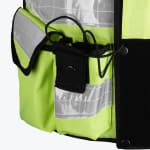 Close-up of a neon yellow safety vest showing a radio pocket with an elastic cord, a flap pocket with reflective tape, and a clear ID window.