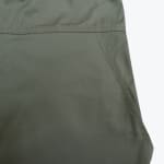 Close-up of an olive green fabric showing a side pocket opening with detailed stitching.