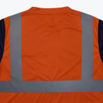 Close-up of the back of an orange high-visibility work shirt with silver reflective stripes.