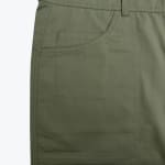 Close-up of a front patch pocket on olive green pants with a smaller coin pocket inside.