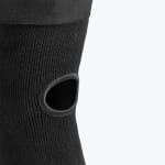 Close-up of a black knitted knee sleeve with a reinforced open patella cutout against a white background.