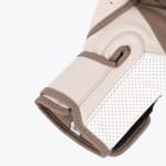 Close-up of a cream and brown leather boxing glove showing the wrist strap, perforated white palm, and stitching details.