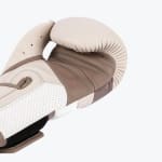 Close-up view of a beige and brown leather boxing glove showing detailed stitching and perforated palm material against a white background.