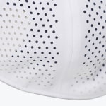 Close-up of white breathable fabric featuring laser-cut perforations and dark blue polka dots, separated by a stitched seam.