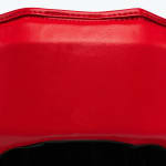 Close-up of a red textured leather material with double stitching along the top edge and a black interior visible below.
