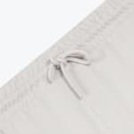 Close-up of a light grey elastic waistband with a matching drawstring tied in a knot.